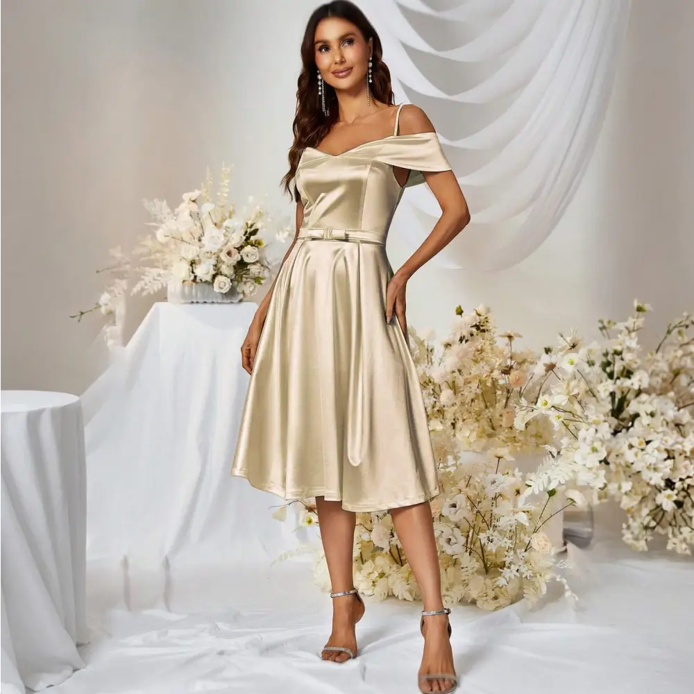 Femme posant dans une robe de mariée cocktail des années 50 avec des bretelles fines et un détail de ceinture, entourée d’une décoration florale élégante