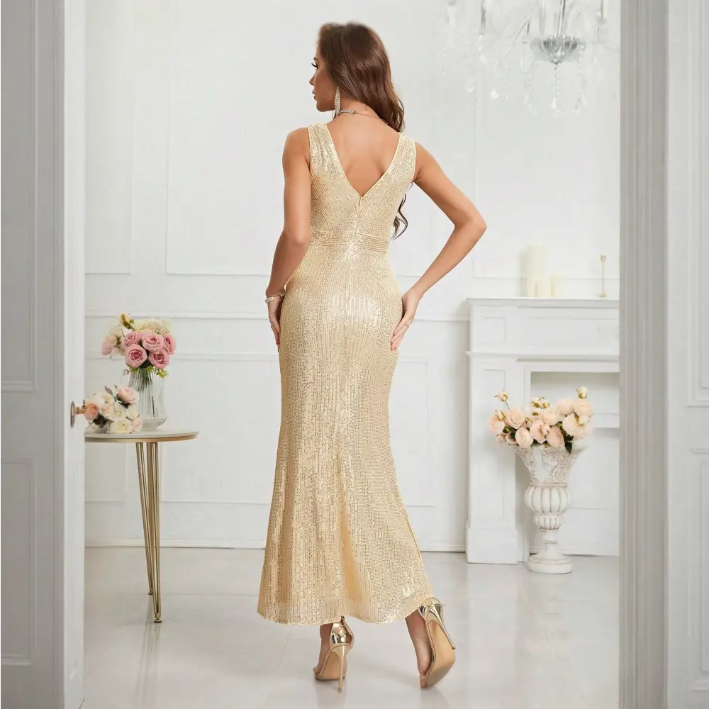 Vue arrière de la robe cocktail dorée. La robe présente un décolleté en V dans le dos et est ornée de paillettes sur toute sa longueur. La coupe ajustée met en valeur la silhouette du mannequin. Le décor luxueux avec des murs blancs et des fleurs ajoute une touche élégante à l’ensemble.