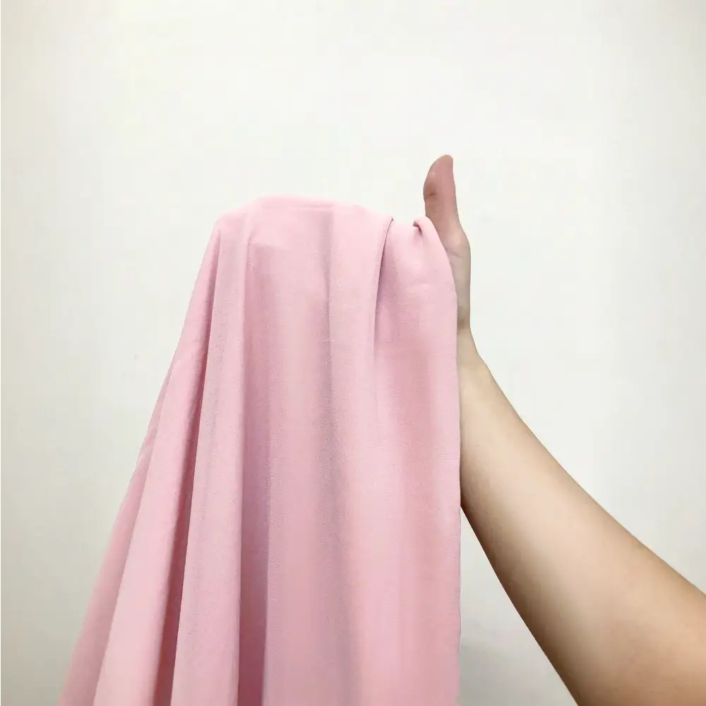 Image en gros plan du tissu en chiffon rose de la robe cocktail grande taille, montrant sa texture douce et fluide.