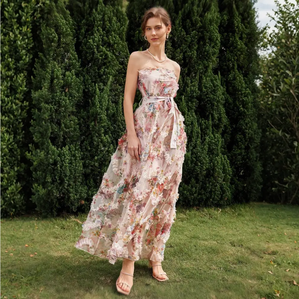 Vue de côté d'une robe cocktail mariage bohème chic, ornée de fleurs colorées et d'un décolleté sans bretelles, portée par une femme dans un cadre naturel.