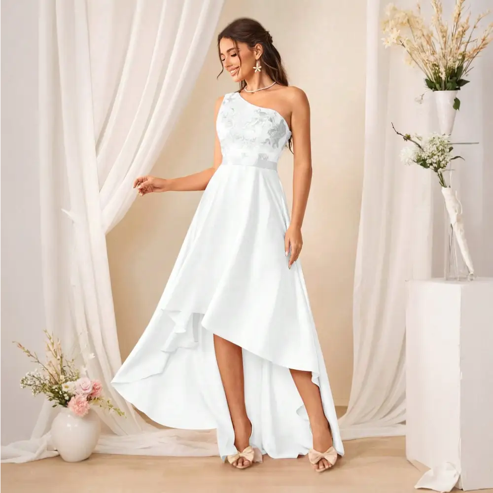 Femme portant une robe de cocktail longue blanche, vue de côté, avec une épaule dénudée et des motifs floraux.