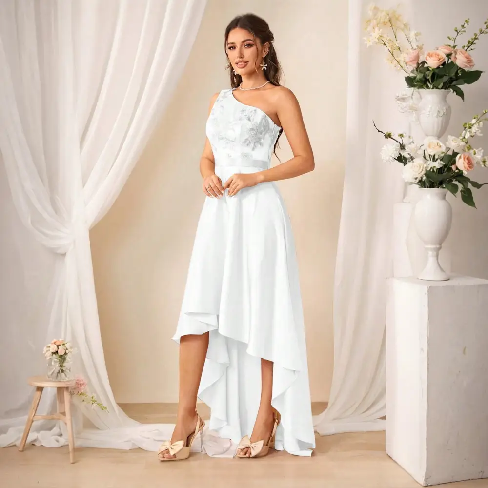 Femme portant une robe de cocktail longue blanche, vue de cote, avec une épaule dénudée et des motifs floraux.