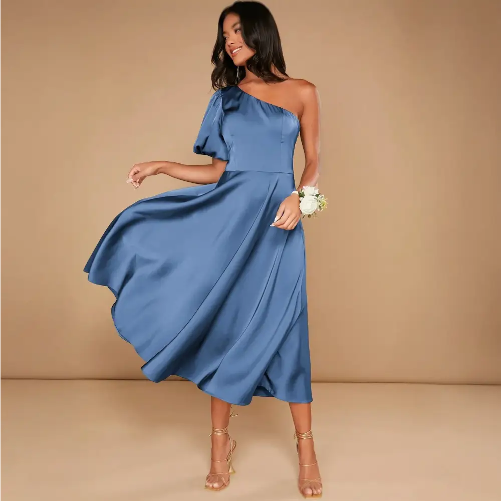 Profil de la femme portant une robe cocktail mariage bleu satinée, montrant les détails de la manche ballon et la coupe asymétrique à une épaule.