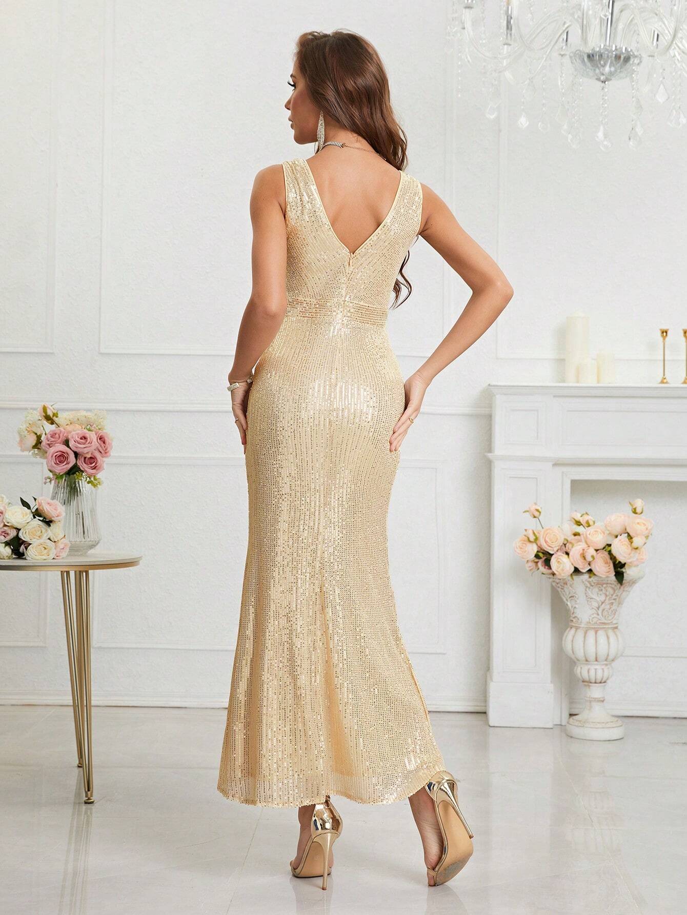 Vue arrière de la robe cocktail dorée. La robe présente un décolleté en V dans le dos et est ornée de paillettes sur toute sa longueur. La coupe ajustée met en valeur la silhouette du mannequin. Le décor luxueux avec des murs blancs et des fleurs ajoute une touche élégante à l’ensemble.