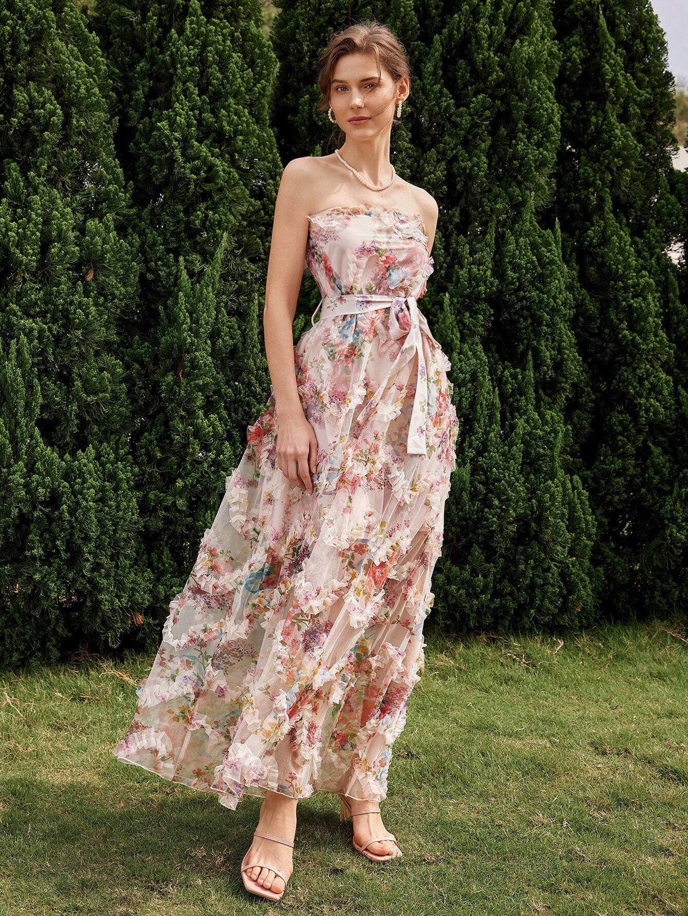 Vue de côté d'une robe cocktail mariage bohème chic, ornée de fleurs colorées et d'un décolleté sans bretelles, portée par une femme dans un cadre naturel.