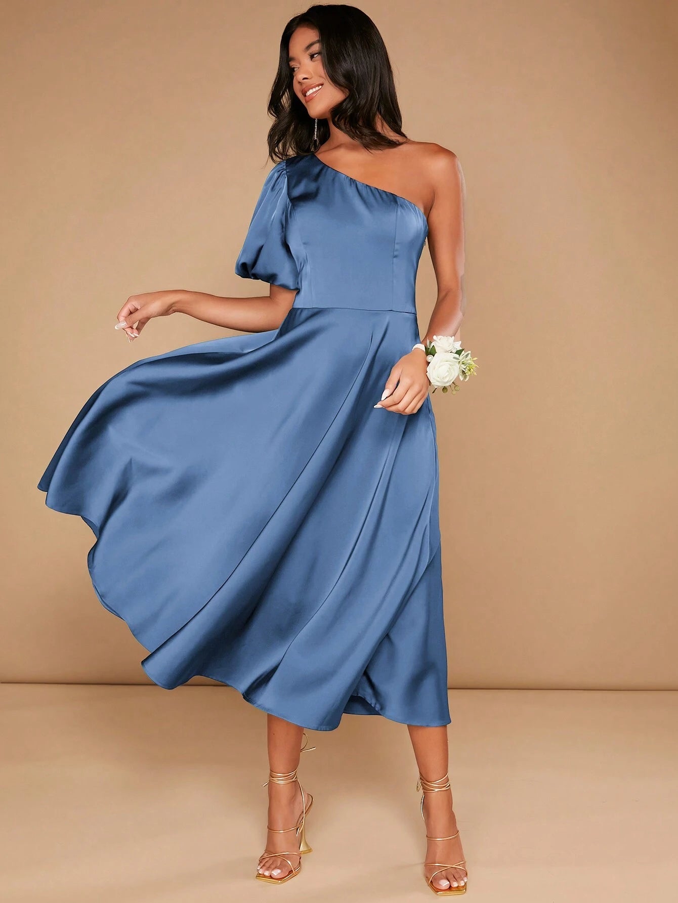 Profil de la femme portant une robe cocktail mariage bleu satinée, montrant les détails de la manche ballon et la coupe asymétrique à une épaule.