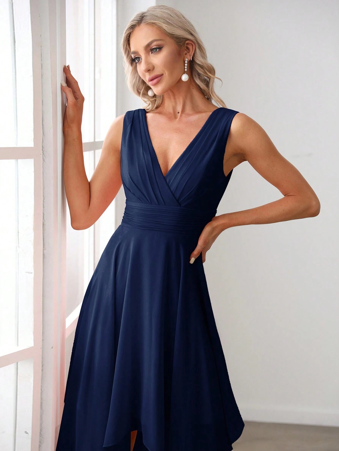 Gros plan d'une femme portant une robe de cocktail bleue pour mariage, mettant en valeur le décolleté en V et les détails plissés de la taille.