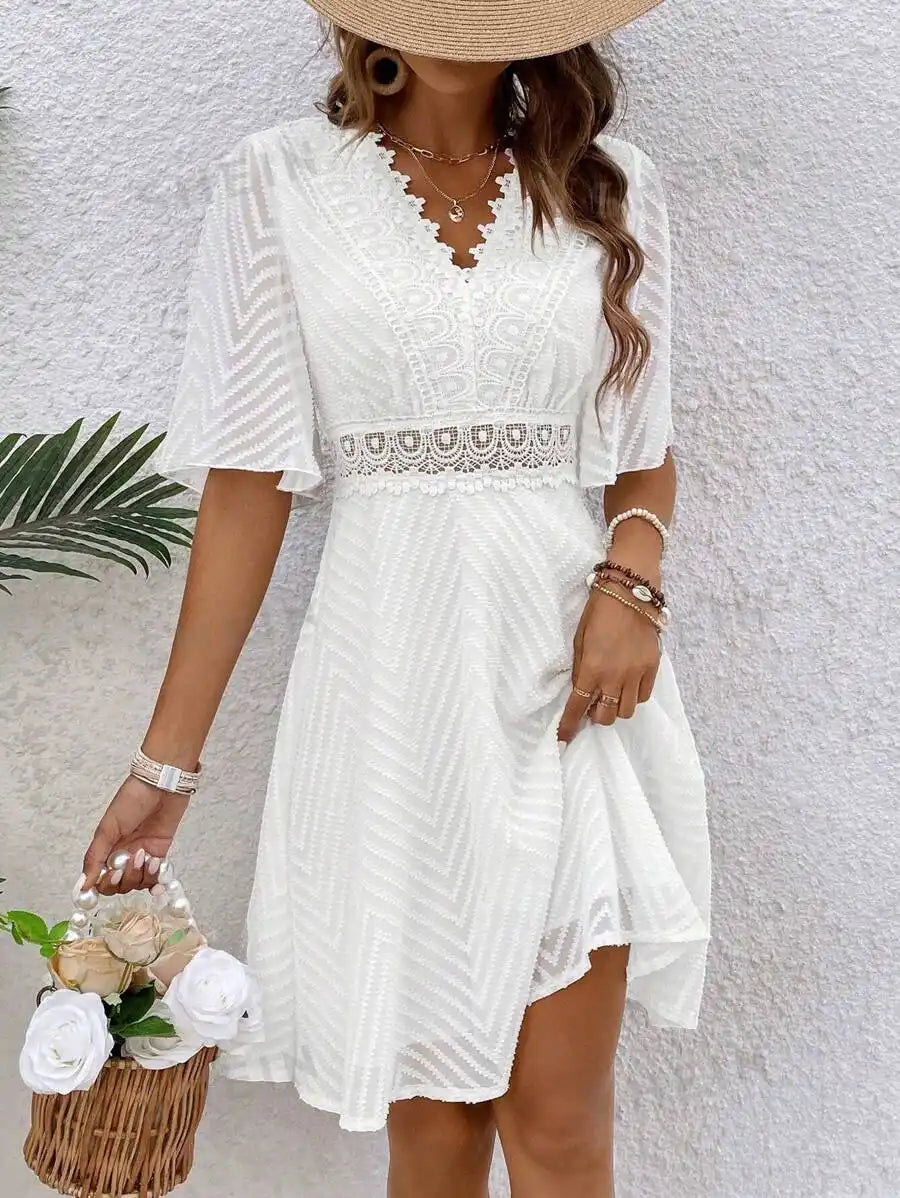 Robe d'été blanche avec des manches flottantes et un détail de ceinture en crochet.