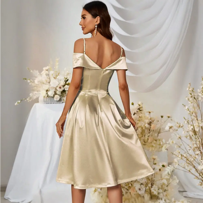 Vue de dos d’une femme portant une robe cocktail des années 50 en satin doré, montrant les détails du dos de la robe avec des bretelles délicates