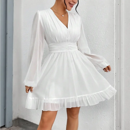 Une charmante robe cocktail blanche vue de face, mettant en valeur un décolleté en V, des manches ¾ fluides, et une ceinture froncée à la taille pour une silhouette élégante.