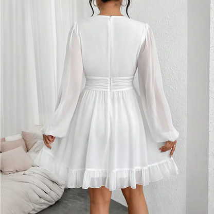 Une élégante robe cocktail blanche vue de dos, avec des manches ¾ légèrement transparentes et une ceinture cintrée à la taille, créant un look féminin et raffiné.