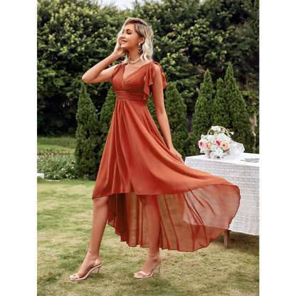 Vue de côté d'une robe cocktail chic originale en terracotta, avec un décolleté en V et des manches courtes, portée par une femme blonde dans un jardin, accompagnée de talons transparents.