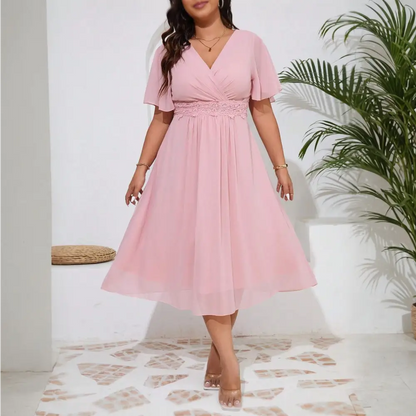 Image de la robe cocktail grande taille en chiffon rose vue de face, portée par un mannequin.