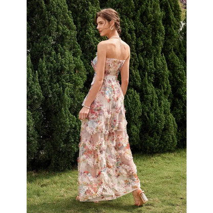Vue de dos d'une élégante robe cocktail mariage bohème chic, avec un imprimé floral délicat, sans bretelles et ceinturée à la taille, portée par une femme dans un jardin verdoyant.