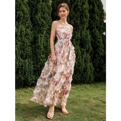 Vue de côté d'une robe cocktail mariage bohème chic, ornée de fleurs colorées et d'un décolleté sans bretelles, portée par une femme dans un cadre naturel.