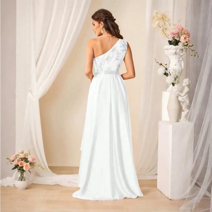 Femme portant une robe de cocktail longue blanche, vue de dos, avec une épaule dénudée et des motifs floraux.