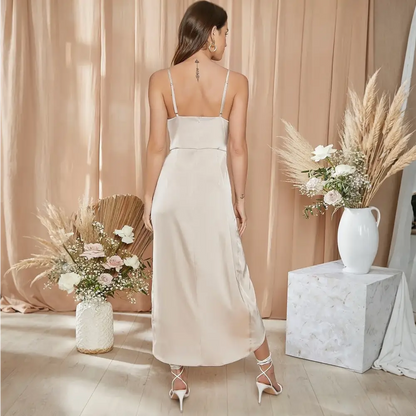 Vue de dos d'une robe de mariée cocktail en satin beige, avec des bretelles fines et une coupe élégante, portée par une femme aux cheveux bruns dans un décor floral sophistiqué.