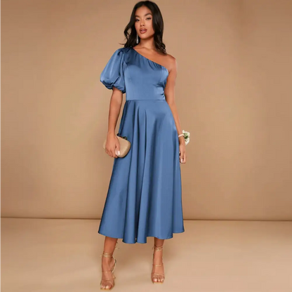 Vue de côté d'une robe cocktail mariage bleu satinée, avec une épaule dénudée et une manche ballon, mettant en valeur la silhouette élégante de la femme.